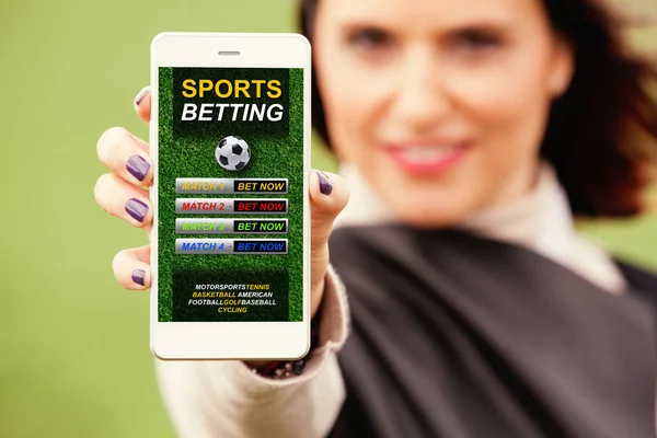Woman showing mobile phone with sports betting website in the screen.