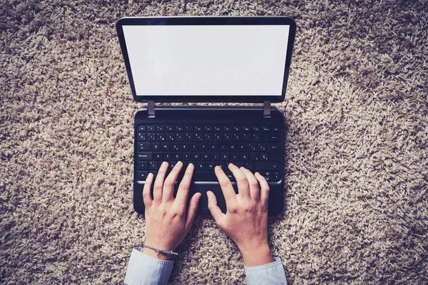 妇女的手在笔记本电脑上打字与白色的空白屏幕 在地板上 — 图库照片