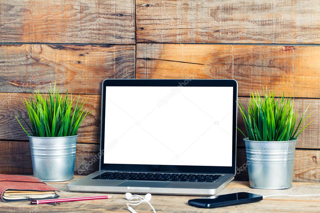 White blank screen on a laptop computer placed on a wooden rustic desk.