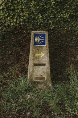 Camino de Santiago post made of stone, with yellow arrow and sign. clipart
