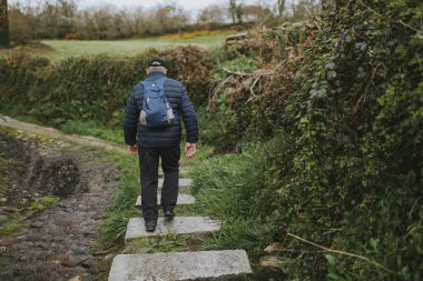 Yeşil manzara ile bir trekking rota yürüyüş bir sırt çantası ile Adam.