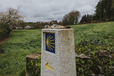 Camino de Santiago post made of stone, with yellow arrow and sign. clipart