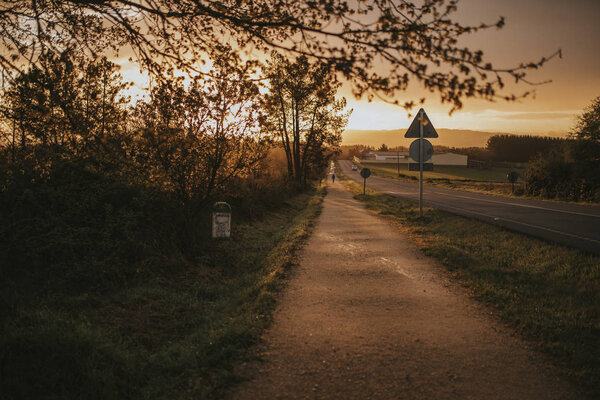 Misterious road during sunrise with a car going in the background.