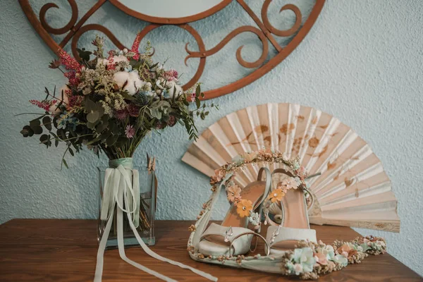 Gelin buketi ve ayakkabı bir masada.