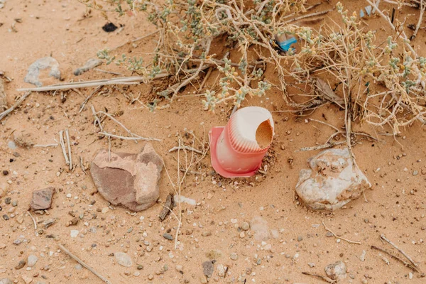 Yoghurt plastic recipient abandoned in the sand. Contamination.