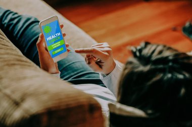 Evde kalırken, sempton denetleyici uygulaması ile sağlık kontrolü için telefon kullanan kadın.