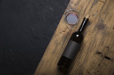 Kırmızı şarap ile bir tirbuşon bir şişe. Siyah bir ahşap arka plan üzerinde