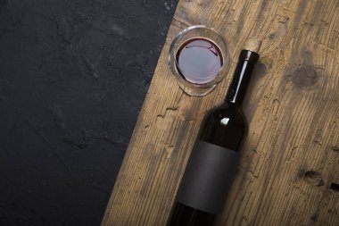 Kırmızı şarap ile bir tirbuşon bir şişe. Siyah bir ahşap arka plan üzerinde