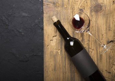 Kırmızı şarap ile bir tirbuşon bir şişe. Siyah bir ahşap arka plan üzerinde