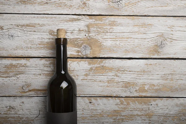 Kırmızı şarap ile bir tirbuşon bir şişe. Siyah bir ahşap arka plan üzerinde