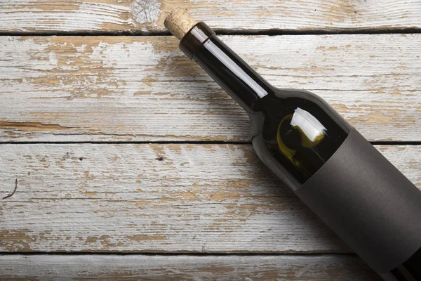 Kırmızı şarap ile bir tirbuşon bir şişe. Siyah bir ahşap arka plan üzerinde