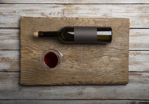 Kırmızı şarap ile bir tirbuşon bir şişe. Siyah bir ahşap arka plan üzerinde