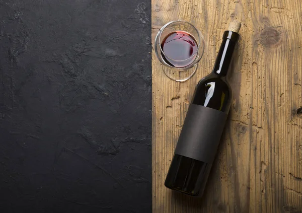Kırmızı şarap ile bir tirbuşon bir şişe. Siyah bir ahşap arka plan üzerinde