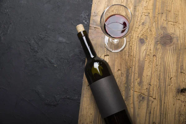 Kırmızı şarap ile bir tirbuşon bir şişe. Siyah bir ahşap arka plan üzerinde