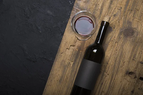 Kırmızı şarap ile bir tirbuşon bir şişe. Siyah bir ahşap arka plan üzerinde