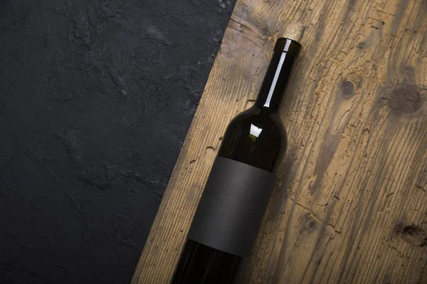 Kırmızı şarap ile bir tirbuşon bir şişe. Siyah bir ahşap arka plan üzerinde
