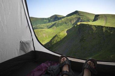 İki kişi dağ manzaralı bir çadırda yalan
