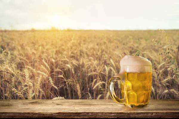 Beer keg with glasses of beer on rural countryside background.