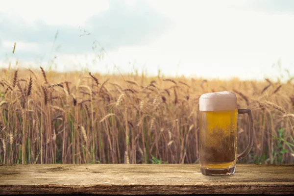 Beer keg with glasses of beer on rural countryside background.