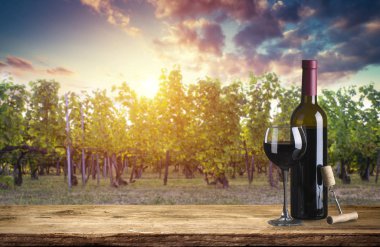 Kırmızı şarap şişesi ve yün fıçıda şarap kadehi. Güzel Toskana arka planı