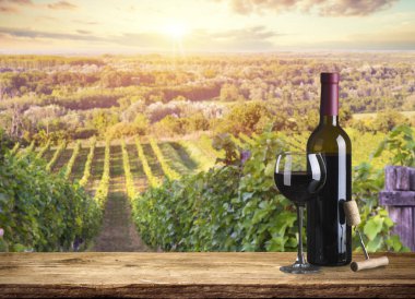 Kırmızı şarap şişesi ve yün fıçıda şarap kadehi. Güzel Toskana arka planı