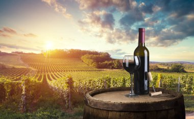 Kırmızı şarap şişesi ve yün fıçıda şarap kadehi. Güzel Toskana arka planı