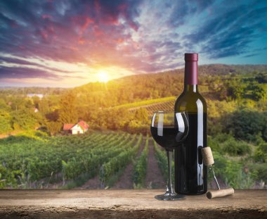 Kırmızı şarap şişesi ve yün fıçıda şarap kadehi. Güzel Toskana arka planı