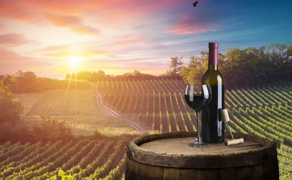 Kırmızı şarap şişesi ve yün fıçıda şarap kadehi. Güzel Toskana arka planı