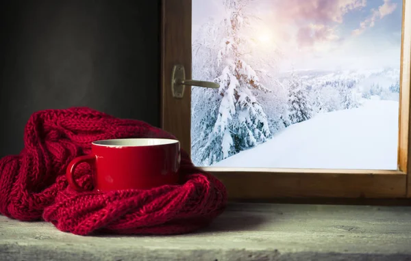 Зимний фон - чашка с леденцом, шерстяной шарф и перчатки на подоконнике и зимняя сцена на открытом воздухе. Натюрморт с концепцией проведения зимнего времени в уютном доме с холодной погодой на открытом воздухе — стоковое фото