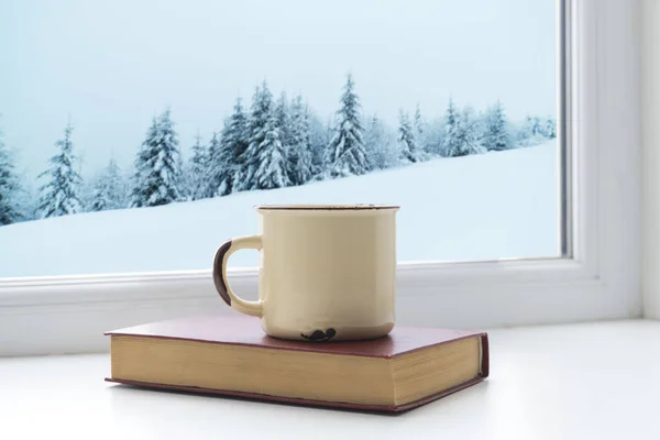 Зимний фон - чашка с леденцом, шерстяной шарф и перчатки на подоконнике и зимняя сцена на открытом воздухе. Натюрморт с концепцией проведения зимнего времени в уютном доме с холодной погодой на открытом воздухе — стоковое фото
