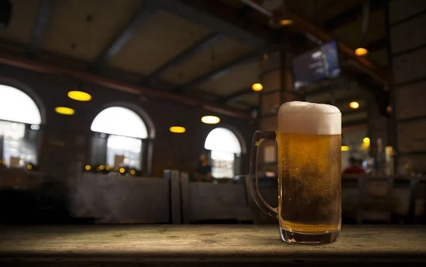 Lunettes avec bière froide sur la table sur fond flou — Photo