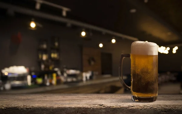 Lunettes avec bière froide sur la table sur fond flou — Photo