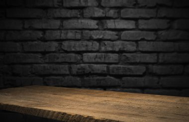Seçili odak boş kahverengi ahşap masa ve duvar dokusu veya eski siyah tuğla duvar arkaplan bulanık görüntüsü. Fotomontaj ya da ürün gösterimi için