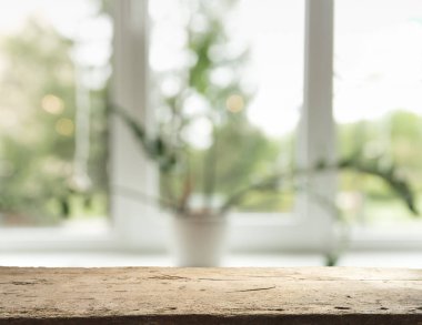 Pencere camından bulanık ahşap masa üstü ve bahçe manzaralı soyut yeşil sabah arka planda. Montaj ürünü görüntüsü için