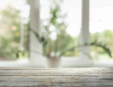 Pencere camından bulanık ahşap masa üstü ve bahçe manzaralı soyut yeşil sabah arka planda. Montaj ürünü görüntüsü için