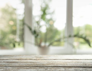 Pencere camından bulanık ahşap masa üstü ve bahçe manzaralı soyut yeşil sabah arka planda. Montaj ürünü görüntüsü için