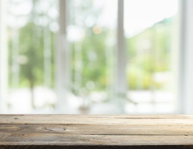 Pencere camından bulanık ahşap masa üstü ve bahçe manzaralı soyut yeşil sabah arka planda. Montaj ürünü görüntüsü için