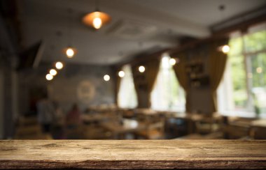 Kafenin soyut bulanık arka planının önündeki boş ahşap masa. Ürünlerinizi görüntülemek veya montajlamak için kullanılabilir. Ürünün görüntülenmesi için modelleyin