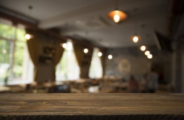 Kafenin soyut bulanık arka planının önündeki boş ahşap masa. Ürünlerinizi görüntülemek veya montajlamak için kullanılabilir. Ürünün görüntülenmesi için modelleyin