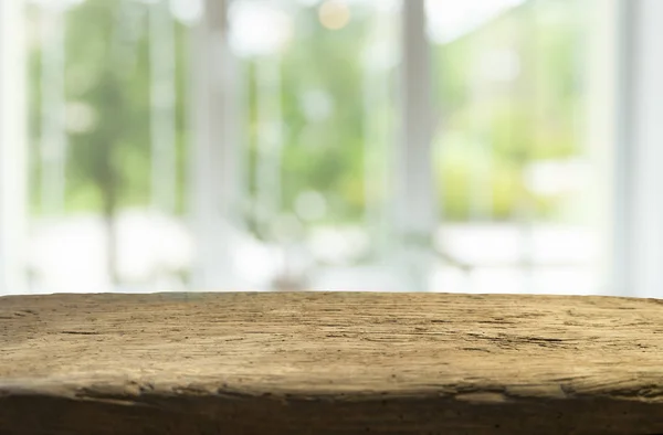 Mesa de madera en desenfoque de cristal de la ventana y verde abstracto del jardín con vista a la ciudad en el fondo de la mañana. Para la exhibición del producto de montaje — Foto de Stock