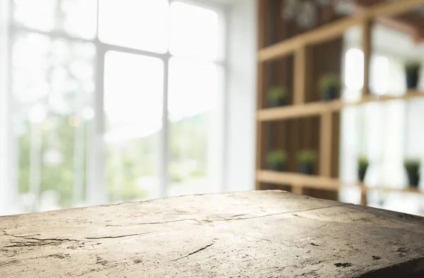 Mesa de madera en desenfoque de cristal de la ventana y verde abstracto del jardín con vista a la ciudad en el fondo de la mañana. Para la exhibición del producto de montaje —  Fotos de Stock