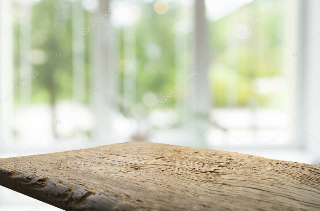 Wood table top on blur of window glass and abstract green from garden with city view in the morning background. For montage product display