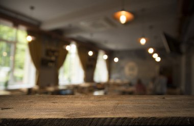 Kafenin soyut bulanık arka planının önündeki boş ahşap masa. Ürünlerinizi görüntülemek veya montajlamak için kullanılabilir. Ürünün görüntülenmesi için modelleyin