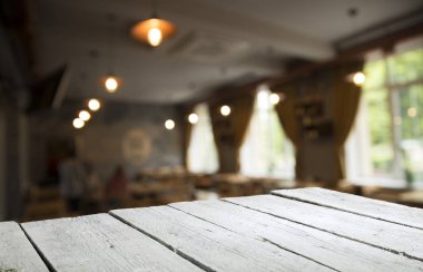 Kafenin soyut bulanık arka planının önündeki boş ahşap masa. Ürünlerinizi görüntülemek veya montajlamak için kullanılabilir. Ürünün görüntülenmesi için modelleyin