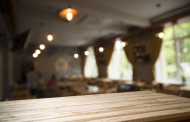 Kafenin soyut bulanık arka planının önündeki boş ahşap masa. Ürünlerinizi görüntülemek veya montajlamak için kullanılabilir. Ürünün görüntülenmesi için modelleyin