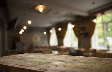 Kafenin soyut bulanık arka planının önündeki boş ahşap masa. Ürünlerinizi görüntülemek veya montajlamak için kullanılabilir. Ürünün görüntülenmesi için modelleyin