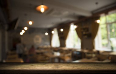Kafenin soyut bulanık arka planının önündeki boş ahşap masa. Ürünlerinizi görüntülemek veya montajlamak için kullanılabilir. Ürünün görüntülenmesi için modelleyin