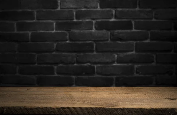 Old wooden table with brick background dark — Stock Photo, Image