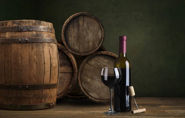 Láhev a sklenice červeného vína na dřevěném sudu střela s tmavým dřevěným pozadím — Stock fotografie