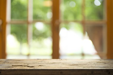 Ağaç bahçe arka planda pencere görünümü yeşil ile perde bulanıklık üzerinde ahşap masa üst boş. Montaj ürün gösterimi veya tasarım anahtarı görsel düzeni için